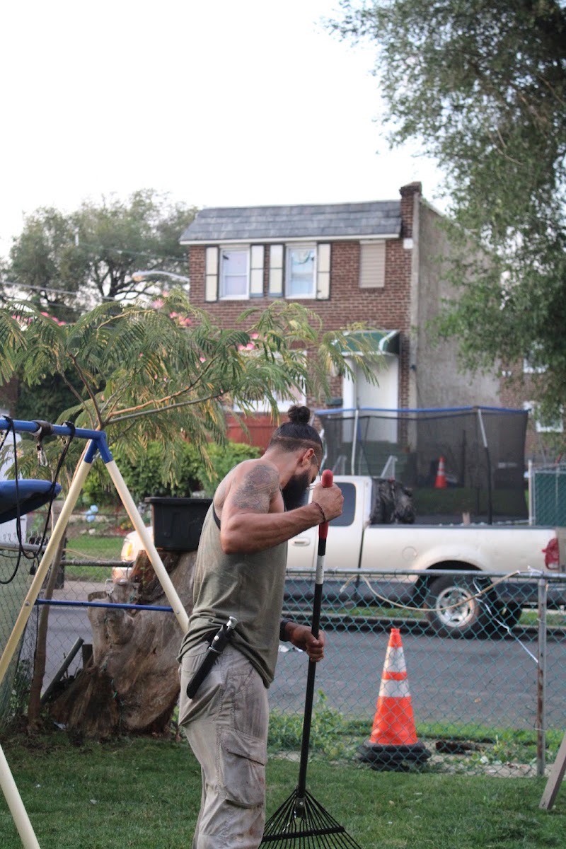 Little Guyz Tree Service crew member raking a residential yard during cleanup